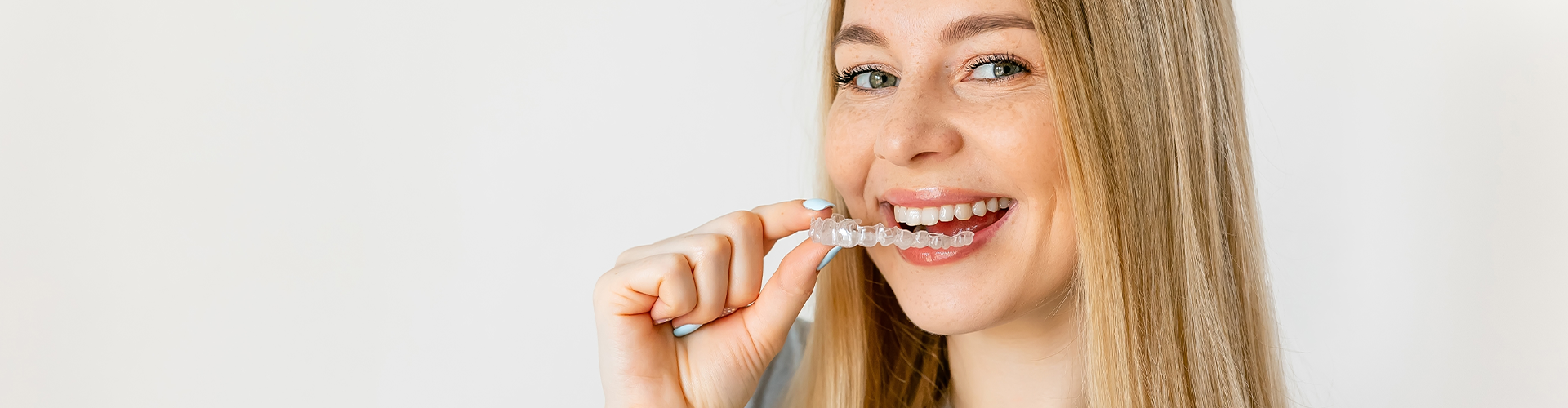 woman placing clear retainer in her mouth